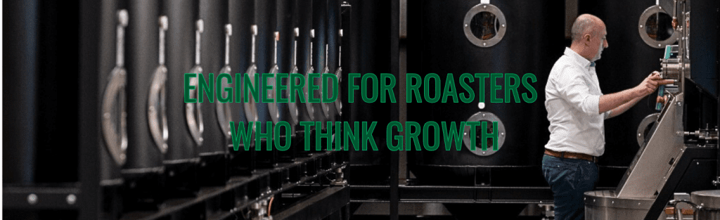 Roast Master operating a large black IMF roasting system with vertical canisters, inside a clean, industrial roasting facility.